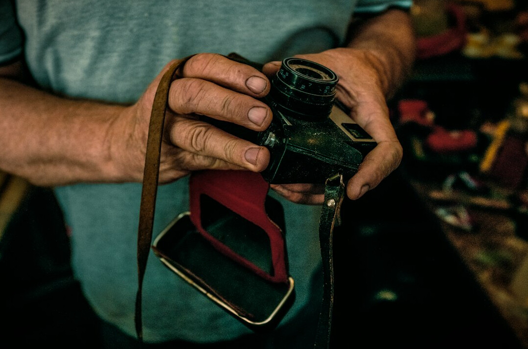 Close-up of hands holding an old film camera