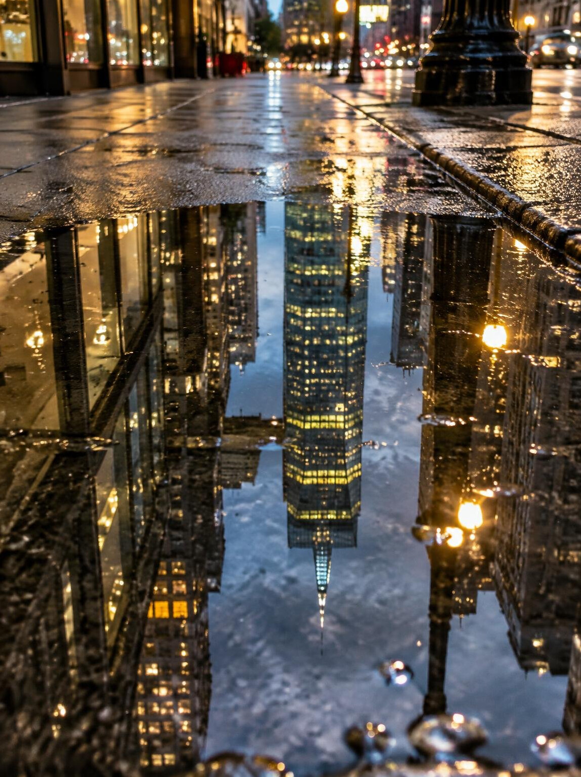 Puddle reflecting city lights and buildings after rain