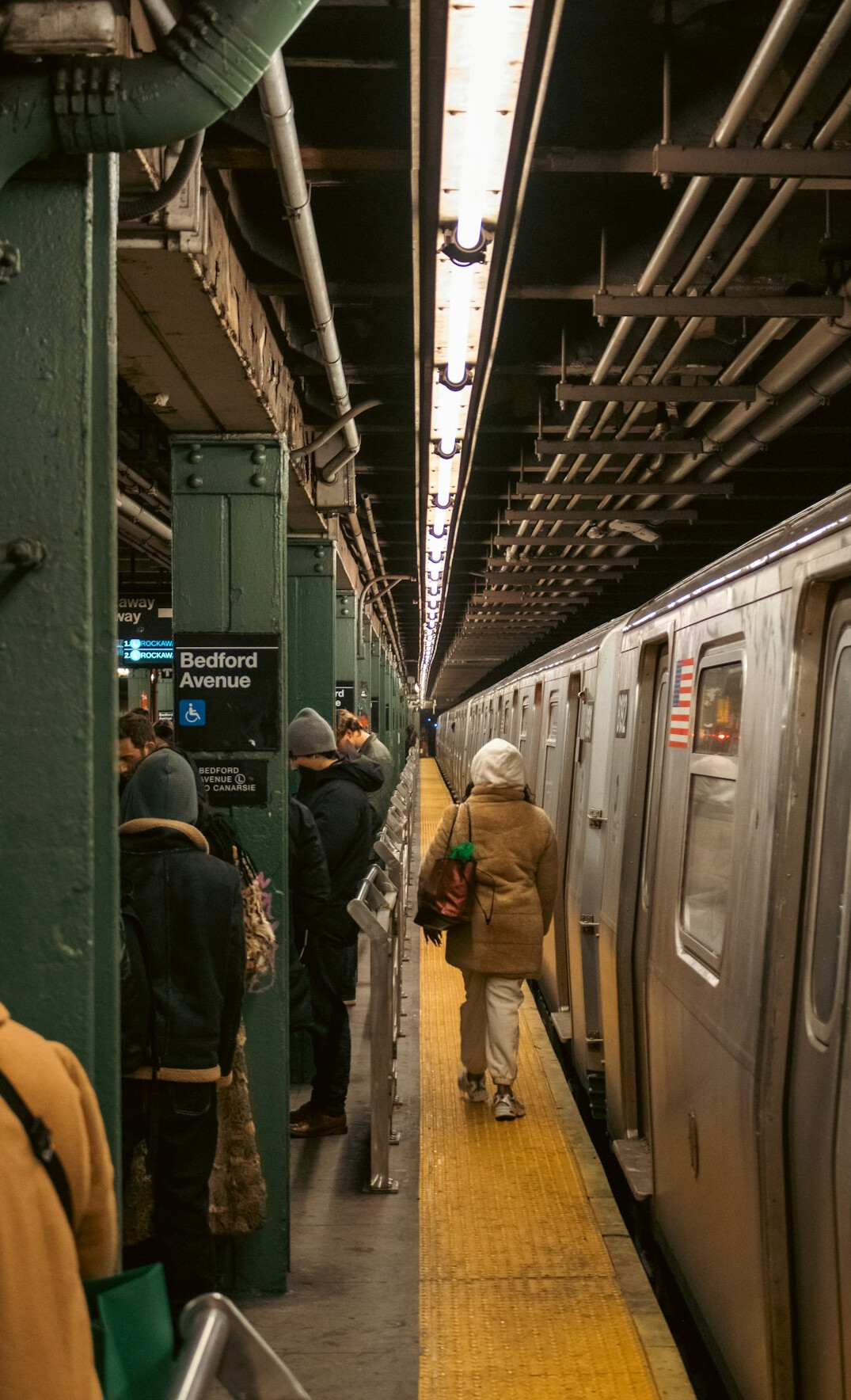 Commuters waiting on a subway platform as a train arrives